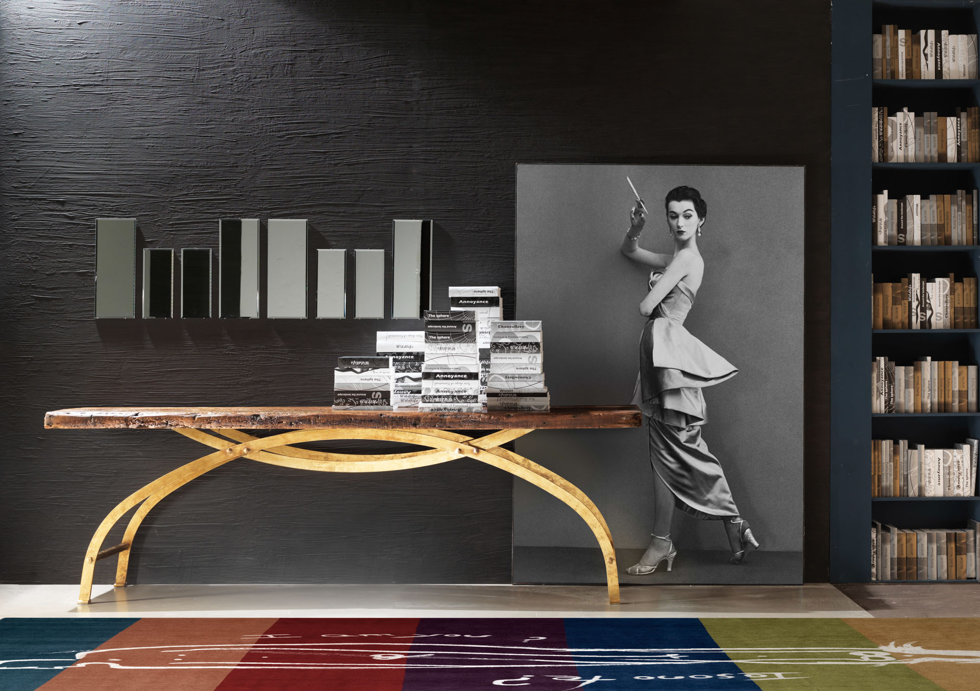 Console di design con piano in legno naturale massiccio e base curva dorata, decorata con libri e quadro di moda vintage. Progetto di design di Bertelè Mobili (Verona).