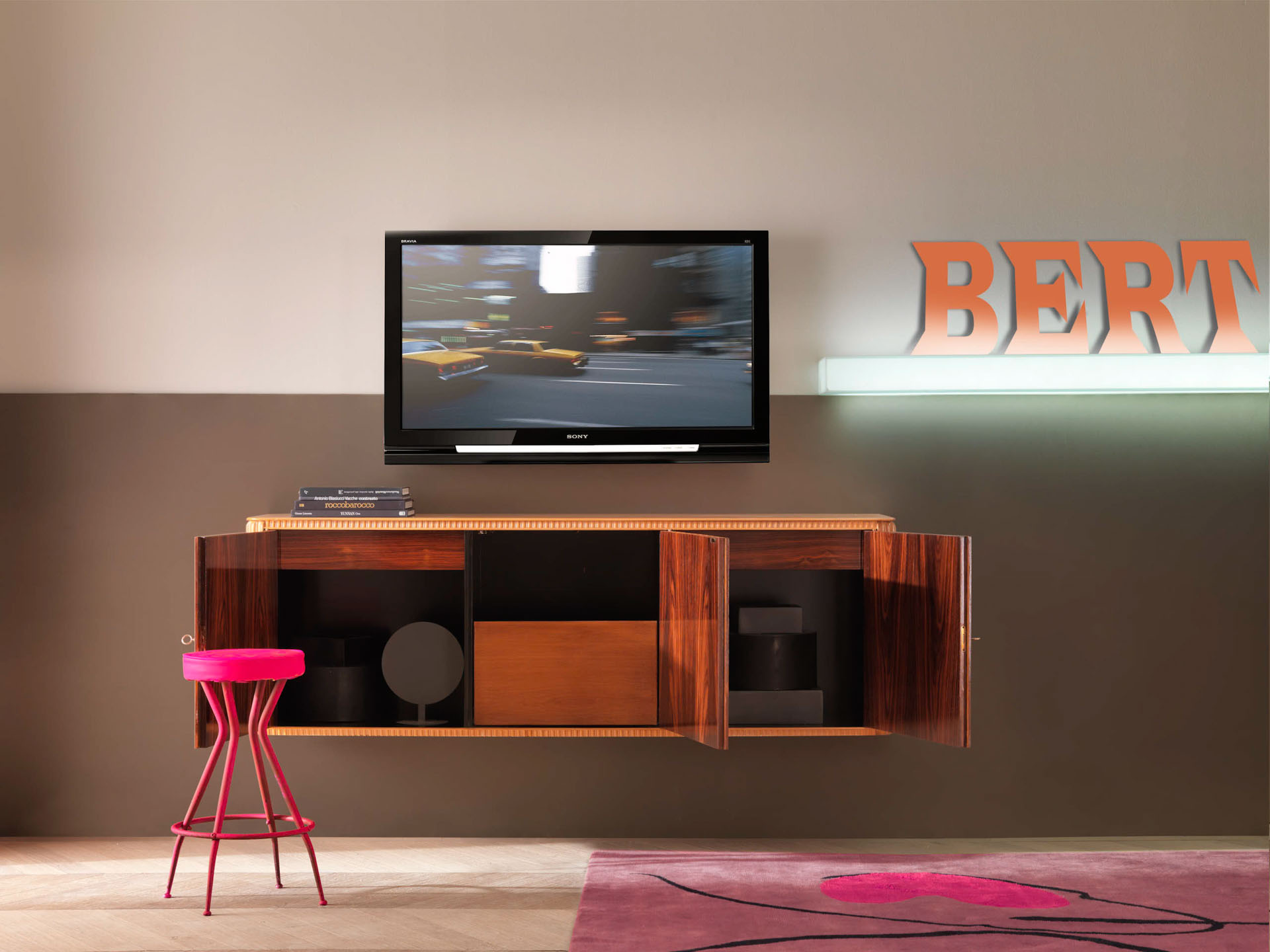 Mobile area lving in legno lucido con sgabello rosa fucsia. Progetto di interior design di Bertelè Mobili (Verona)