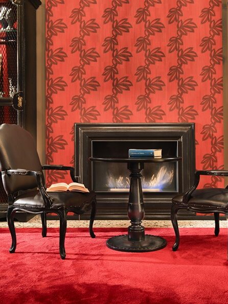 Sedie e tavolo in legno scuro, camino scuro in ambiente rosso. Interior design per hotel di lusso, a cura di Bertelè Mobili